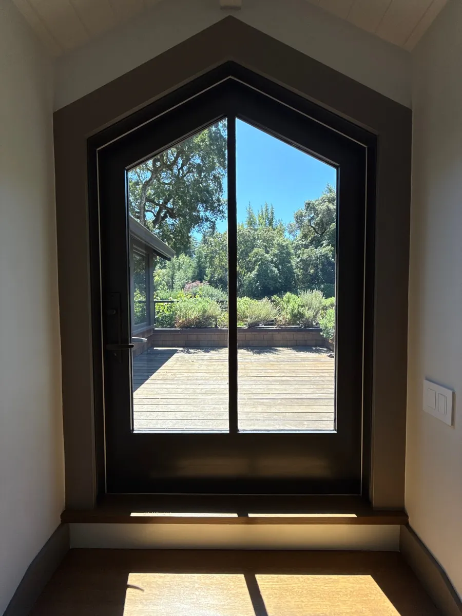 Peaked-arch glass entry door looking out to a deck, window film on the glass